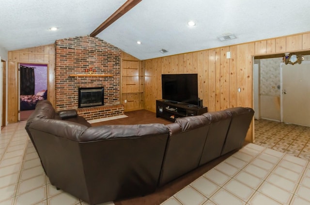 living room featuring vaulted ceiling with beams, a fireplace, a textured ceiling, and wooden walls