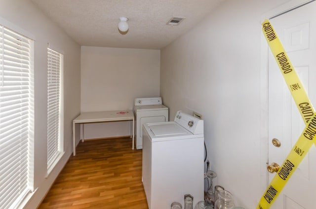 washroom featuring a textured ceiling, separate washer and dryer, and light hardwood / wood-style flooring