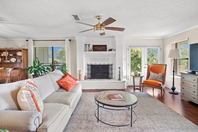 living room featuring a fireplace, a textured ceiling, hardwood / wood-style flooring, and ornamental molding