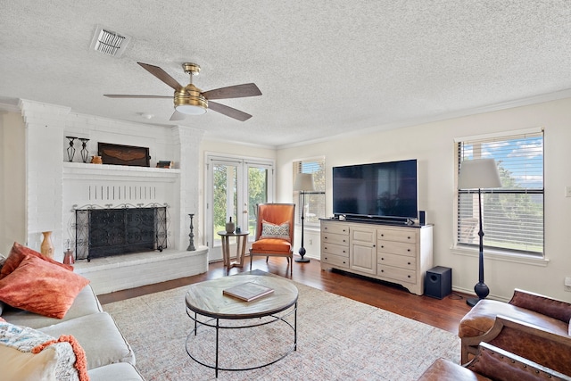 living room featuring a fireplace, a textured ceiling, and crown molding