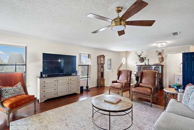 living room with ceiling fan, dark hardwood / wood-style flooring, ornamental molding, and a textured ceiling