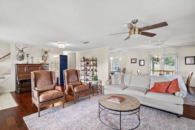 living room with ceiling fan with notable chandelier, dark hardwood / wood-style flooring, a textured ceiling, and crown molding