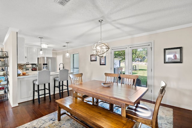 dining space featuring ornamental molding, dark hardwood / wood-style floors, a textured ceiling, and an inviting chandelier