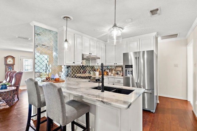 kitchen with light stone countertops, white cabinetry, hanging light fixtures, stainless steel appliances, and kitchen peninsula