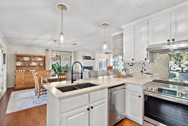 kitchen with kitchen peninsula, stainless steel appliances, sink, decorative light fixtures, and white cabinets