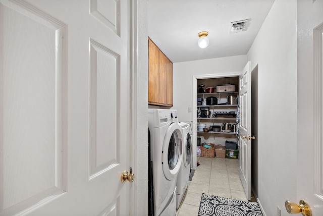 washroom with light tile patterned flooring, cabinets, and washing machine and clothes dryer