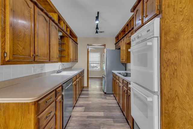 kitchen featuring backsplash, track lighting, sink, hardwood / wood-style flooring, and stainless steel appliances