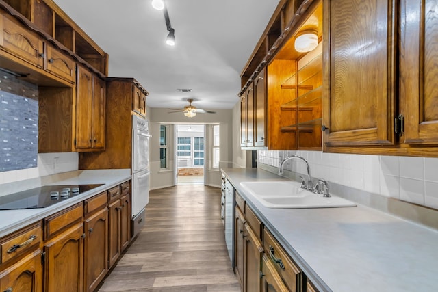 kitchen featuring black electric stovetop, light wood-type flooring, backsplash, ceiling fan, and sink