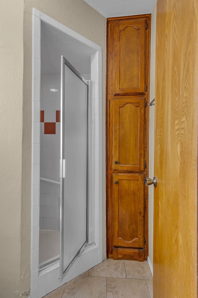 bathroom with tile patterned floors and a shower with door