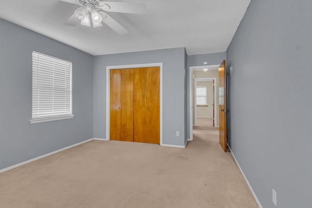 unfurnished bedroom featuring light carpet, a closet, and ceiling fan