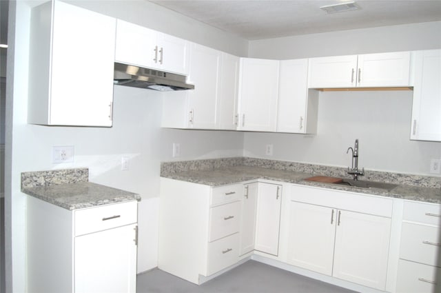 kitchen featuring white cabinetry, sink, and light stone countertops