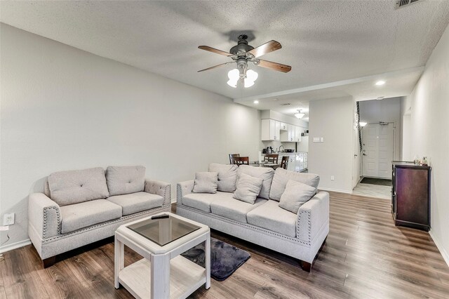 living room with hardwood / wood-style floors, ceiling fan, and a textured ceiling