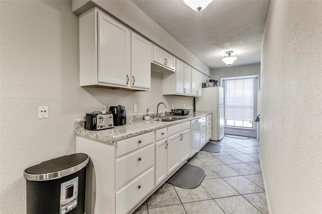 kitchen with sink, white appliances, white cabinetry, and a textured ceiling