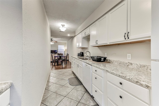 kitchen featuring ceiling fan, sink, white dishwasher, a textured ceiling, and white cabinets