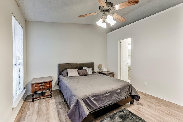 bedroom featuring connected bathroom, ceiling fan, light hardwood / wood-style flooring, and a textured ceiling