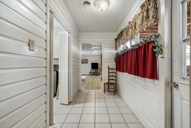 hall with light tile patterned floors, visible vents, and a wealth of natural light