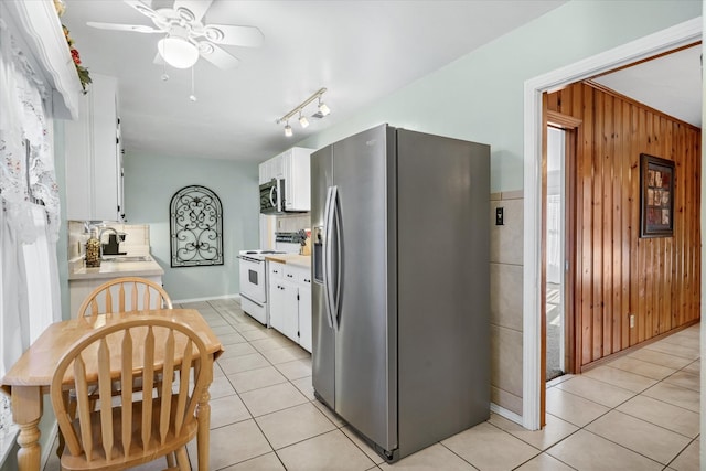 kitchen featuring white cabinets, appliances with stainless steel finishes, light countertops, wood walls, and a sink