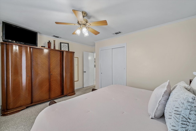 carpeted bedroom featuring a ceiling fan, a closet, visible vents, and crown molding