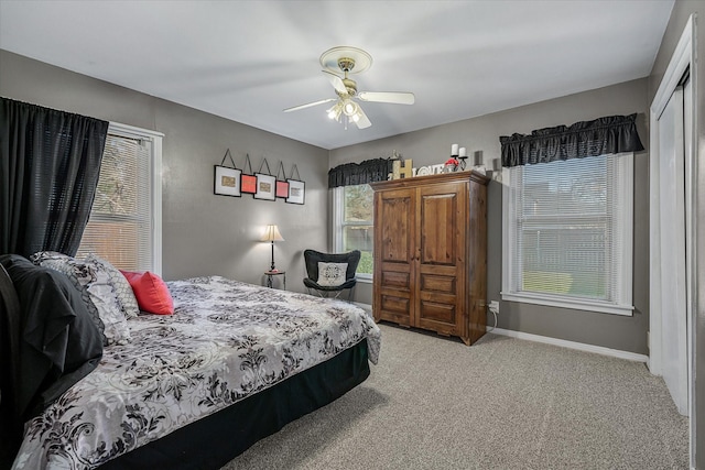 bedroom featuring a ceiling fan, a closet, light carpet, and baseboards