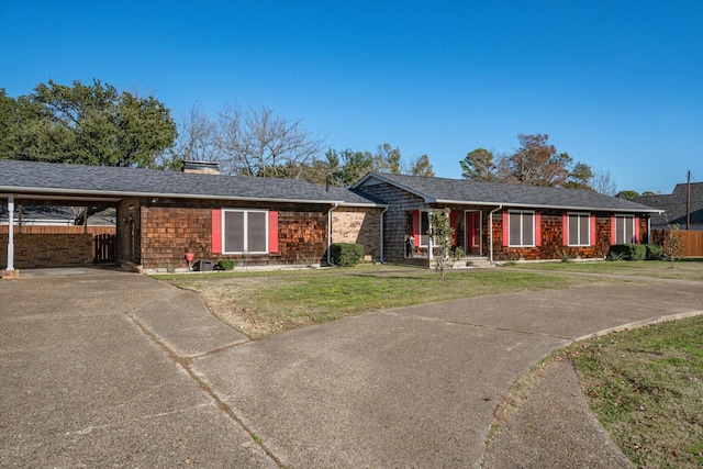 ranch-style house featuring a shingled roof, concrete driveway, fence, a carport, and a front lawn