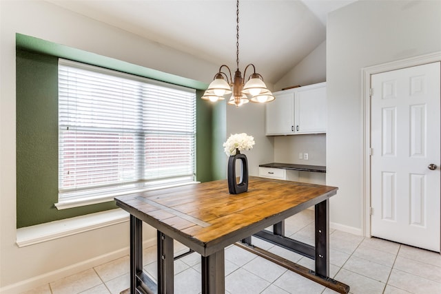 tiled dining room featuring a chandelier and vaulted ceiling