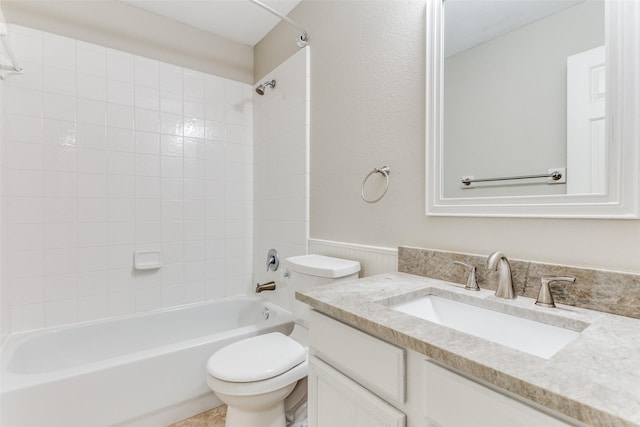 full bathroom featuring tiled shower / bath, vanity, and toilet