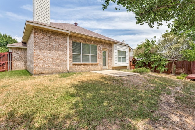 rear view of house with a lawn and a patio