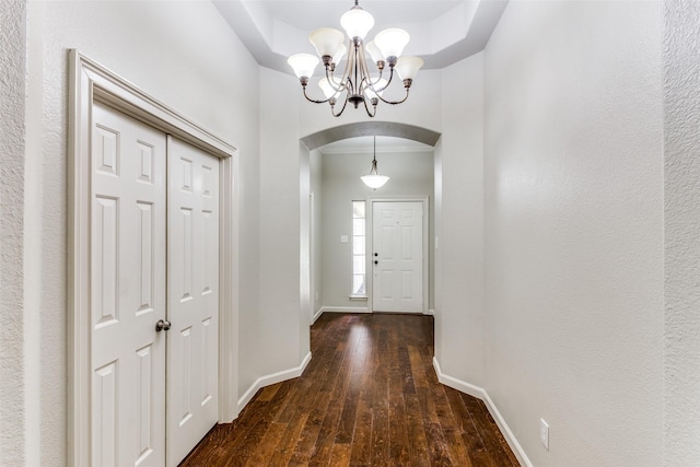 entryway featuring ornamental molding, dark wood-type flooring, and a chandelier