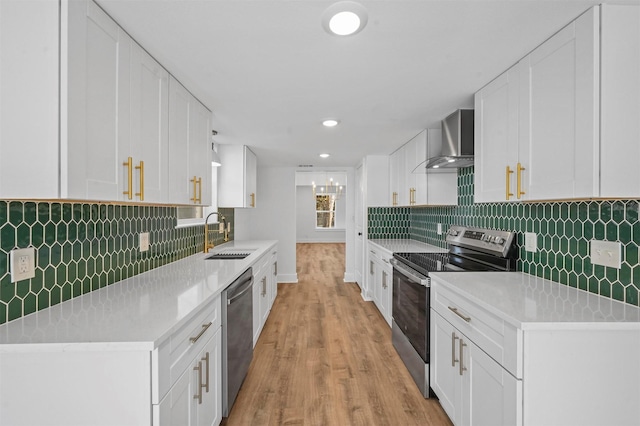 kitchen featuring stainless steel appliances, white cabinetry, sink, and wall chimney exhaust hood