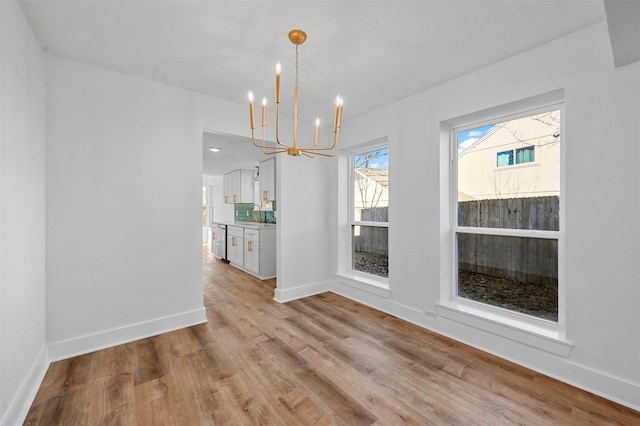 unfurnished dining area featuring an inviting chandelier and light wood-type flooring