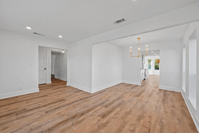 spare room featuring french doors, light hardwood / wood-style flooring, and a notable chandelier