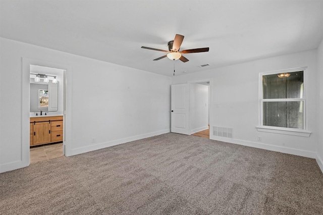 unfurnished bedroom with ensuite bathroom, ceiling fan, and light colored carpet