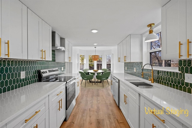 kitchen with pendant lighting, white cabinetry, stainless steel appliances, and sink