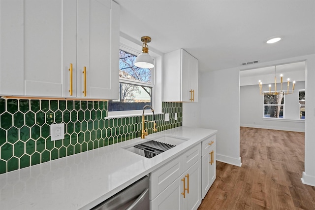 kitchen with white cabinetry, sink, pendant lighting, and backsplash