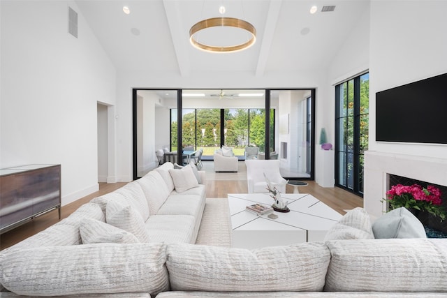 living room featuring hardwood / wood-style flooring, a high end fireplace, high vaulted ceiling, and beamed ceiling