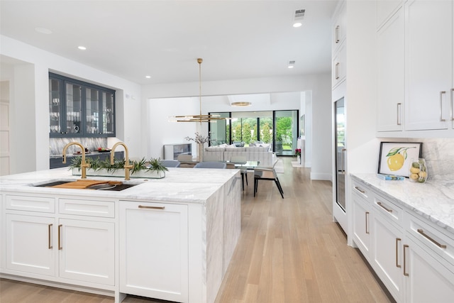 kitchen featuring white cabinets, decorative light fixtures, and sink