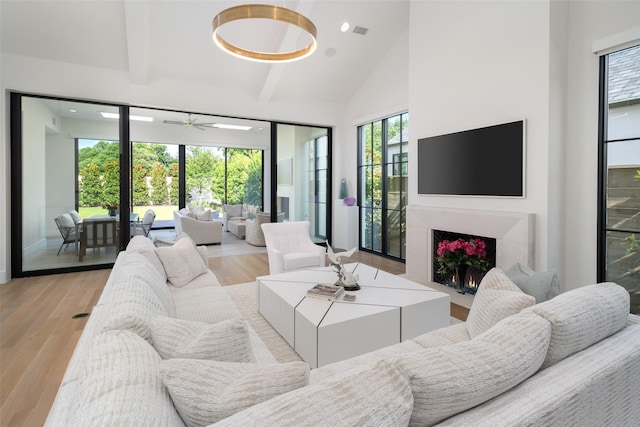 living room with beam ceiling, ceiling fan, high vaulted ceiling, and light wood-type flooring