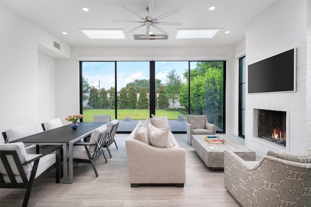 living room featuring a wealth of natural light, a brick fireplace, and ceiling fan