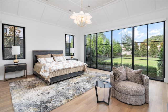 bedroom with a chandelier, light hardwood / wood-style floors, and coffered ceiling