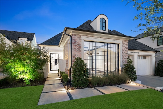 french country inspired facade with a front yard and a garage