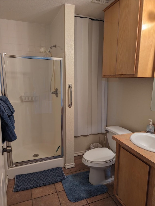 bathroom with tile patterned flooring, vanity, toilet, and walk in shower