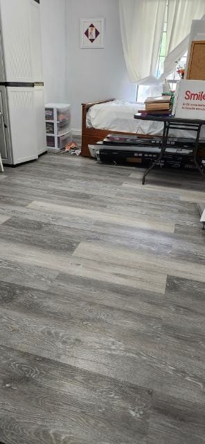 bedroom with wood-type flooring and white fridge