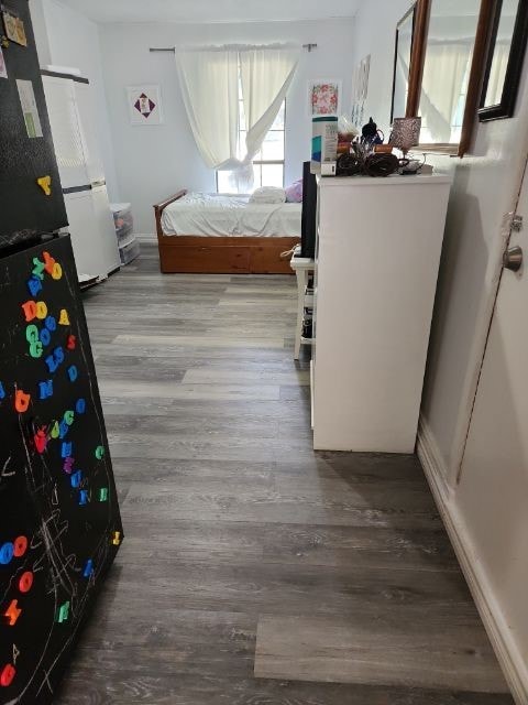 bedroom featuring wood-type flooring and black fridge