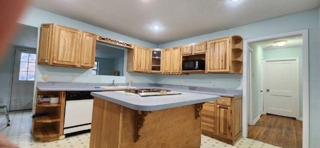 kitchen with sink, a kitchen breakfast bar, white dishwasher, stainless steel gas cooktop, and a kitchen island