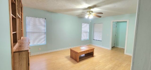 unfurnished room with ceiling fan, a textured ceiling, and light wood-type flooring