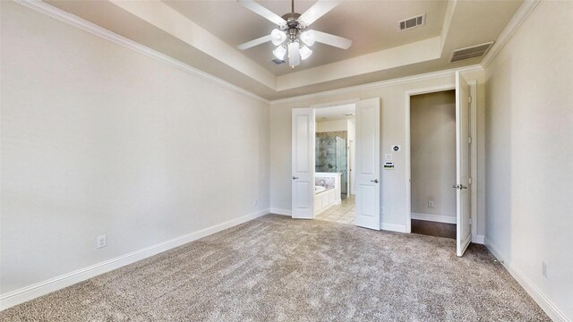 unfurnished bedroom featuring ensuite bath, light colored carpet, a raised ceiling, and ceiling fan