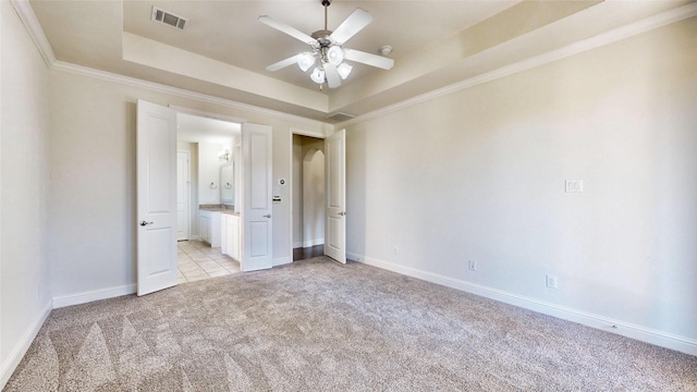 unfurnished bedroom with a tray ceiling, ceiling fan, crown molding, and light colored carpet