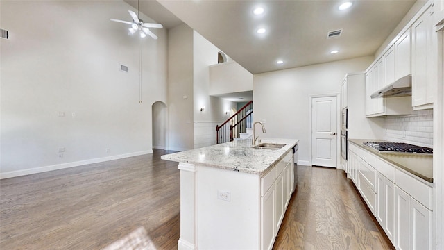 kitchen with a kitchen island with sink, ventilation hood, white cabinets, sink, and hardwood / wood-style flooring