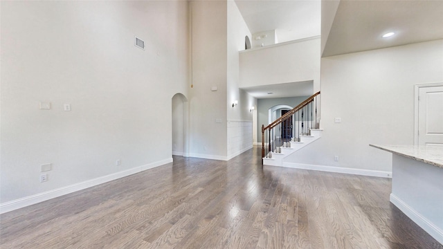 unfurnished living room featuring hardwood / wood-style floors and a high ceiling