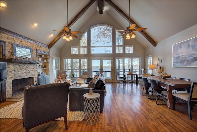 living room featuring high vaulted ceiling, plenty of natural light, and a stone fireplace